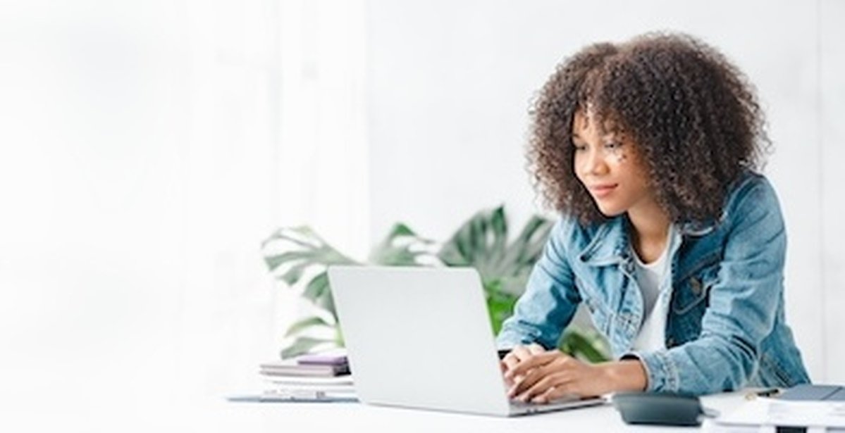 Amerikanische Teenager-Frau sitzt in weißen Büro mit Laptop, sie ist ein Student studiert online mit Laptop zu Hause, Studentin studiert online, Online-Web-Bildung Konzept.
