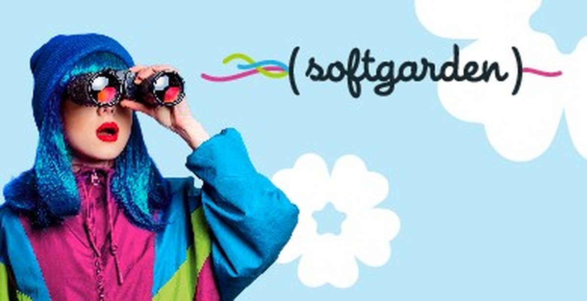 Eine Frau mit blauen Haaren mit einem Verglas vor dem Gesicht und einer bunten Jacke und in klammern steht softgarden