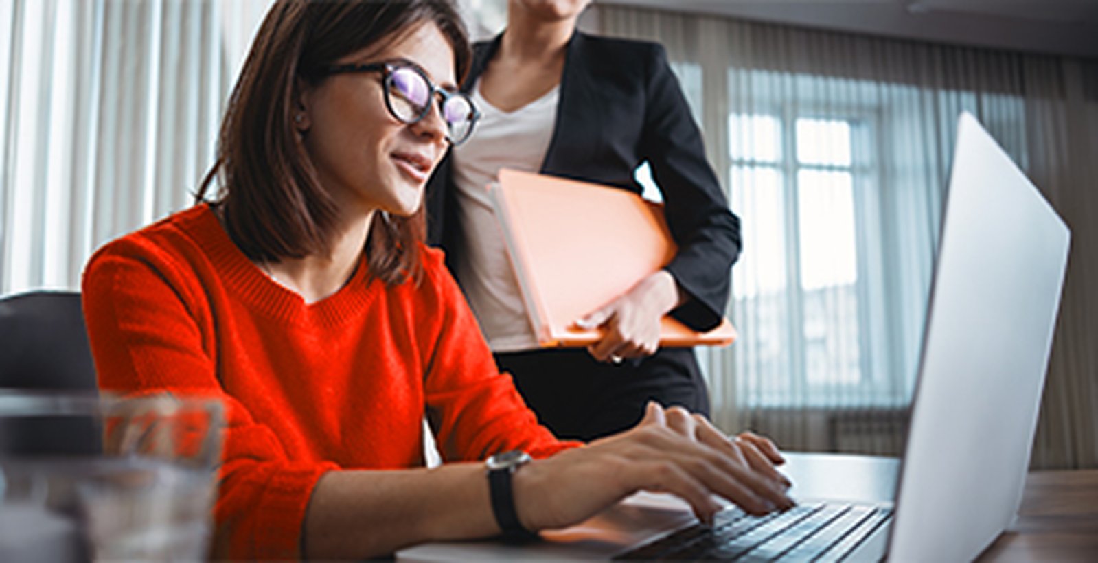 ein Frau mit Brille sitzt am Arbeitsplatz am PC